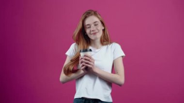 Genç kızıl saçlı, mühendis miğferiyle iyimser bir şekilde gülümsüyor ve kendinden emin bir şekilde ileriye bakıyor. Beyaz tişörtlü, pembe arka planda izole edilmiş çilli genç kız. İnsan kavramı.