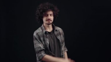 Karizmatik genç adam işaret parmağıyla bir tarafı işaret ediyor, iki eliyle birden, birkaç kez. Siyah arka planda izole edilmiş, yaşam kavramı. İnsanların duyguları işte. 4k portre