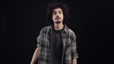 Genç hippi dikkatlice bakar, harika bir şey görür, haykırır ve şevkli görünür. Siyah arka planda izole edilmiş, yaşam kavramı. İnsanların duyguları işte. 4k portre