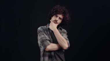 Eli çenesinde düşünen bir hipsterin portresi, analiz eder, onu çok mutlu eden bir fikre kapılır, öyle görünür. Siyah arka planda izole edilmiş, yaşam kavramı. İnsanların duyguları.