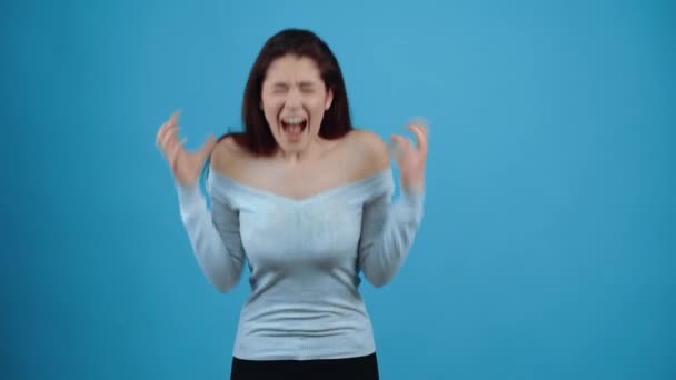 Раздраженная молодая женщина кричит изо всех сил с сжатыми кулаками, а затем показывает сердитым и расстроенным лицом. Азиат с темными волосами, одетый в синюю блузку, изолированный на темно-синем фоне в — стоковое видео