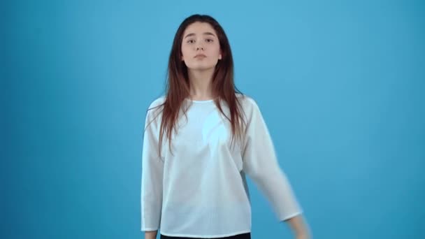 El retrato de una joven carismática que, como muestra de respeto, da la espalda y realiza un saludo militar. Asiática de pelo oscuro, vestida con blusa azul, aislada sobre fondo azul oscuro — Vídeo de stock