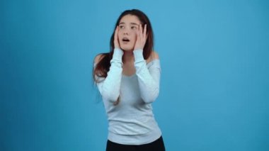 The portrait of a charismatic young woman seems to pantomime with her hands. Asian with dark hair, dressed in a blue blouse, isolated on a dark blue background in the studio. The lifestyle concept of