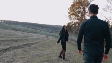 Genç aşıklar yeşil çayırda yürürler, kadın sırtı önde koşar geniş bir gülümsemeyle, adam onu mutlu bir şekilde takip eder. Doğanın kalbinde, bir çayırda, ağaçlarla izole edilmiş.