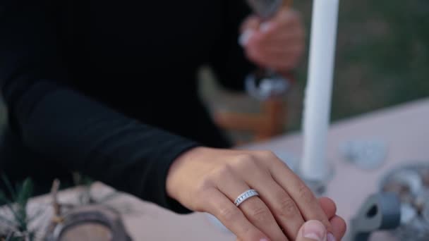 Cadrul apropiat al mâinii femeii care are un inel de logodnă pe degetul ei ineral, mâna omului o apucă și o ține strâns de mână, pe un fundal încețoșat. Conceptul de stil de viață al tinerilor îndrăgostiți — Videoclip de stoc