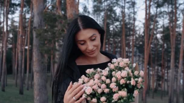 La mujer feliz huele el ramo de rosas blancas, en el seno de la naturaleza, en el prado verde, cerca de la mesa para la cena romántica — Vídeos de Stock