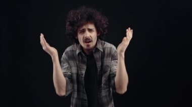 Somurtkan genç bir adamın portresi, kötü bir şekilde şok geçirir, ne der, ve ellerini umutsuzca kafasına koyar. Siyah arka planda izole edilmiş, yaşam kavramı. İnsanların duyguları işte. 4k portre