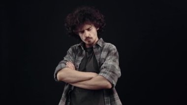 Kızgın çocuk ellerini göğsünde çapraz yapar, kaşlarını çatar, kulaklarını parmaklarıyla kapatır, inatla hayır der. Siyah arka planda izole edilmiş, yaşam kavramı. İnsanların duyguları işte. 4k portre