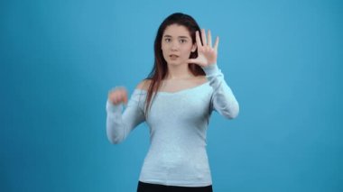Görünmez bir kutuya kilitlenmiş genç kadın ellerini cama koyup neler olduğunu anlamaya çalışıyor. Pandomim konsepti. Koyu saçlı, mavi bluz giymiş, koyu tenli bir Asyalı.