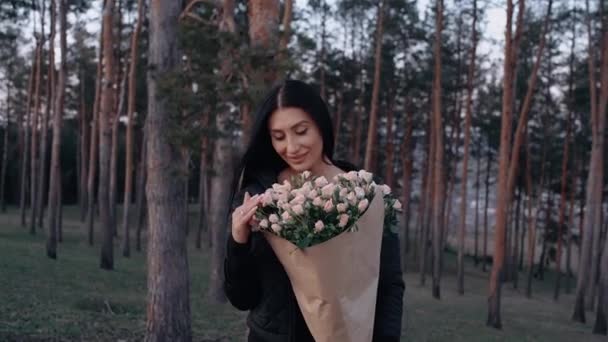 De jonge brunette, gelukkig, houdt in haar hand een groot boeket van roze rozen gegeven door haar vriend — Stockvideo