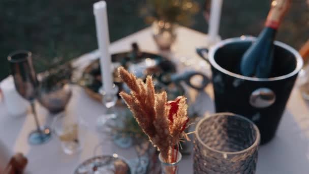 Bliska rama naturalnego otoczenia, stół ozdobiony romantycznymi elementami, sztućce, dzikie kwiaty, sambanie i świece — Wideo stockowe