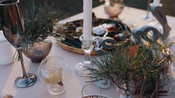 Den perfekta bilden av ett bord i naturens sköte med tallgrenar, glas, ljus och bestick. Stäng ramen. Romantiskt begrepp — Stockvideo