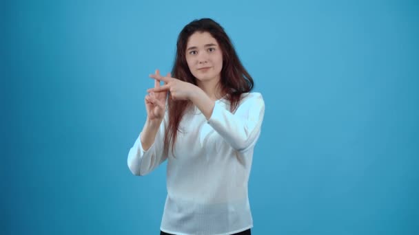 Portret van een mooi meisje met haar handen onder het hashtag bord om haar heen. Aziatisch met donker haar, gekleed in een blauwe blouse, geïsoleerd op een donkerblauwe achtergrond in de studio. De levensstijl — Stockvideo