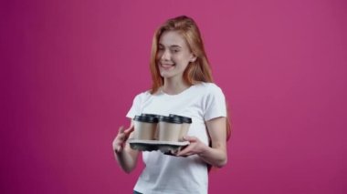 Kızıl saçlı, iyimser, karizmatik öğrenci elinde dört kahveyle bir tanesini alıp birine uzatıyor. Beyaz tişörtlü çilli genç, pembe arka planda izole edilmiş. Konsept