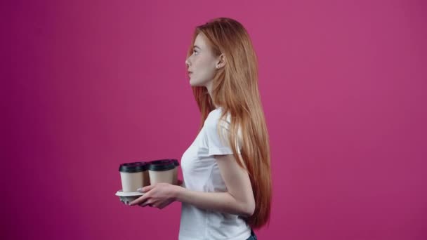 若い赤毛、親切で楽観的な4つのコーヒーでサポートを提供しています。白いTシャツに身を包んだ10代の若者たちは、ピンクの背景に孤立していた。人々の生活様式の概念 — ストック動画