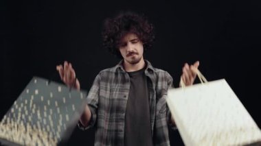 İyimser hippi geniş bir gülümsemeyle iki paket alır, mutlu ve tatmin olur. Alışverişin keyfi. Siyah arka planda izole edilmiş. Hayat kavramı. İnsanların duyguları işte. 4k portre