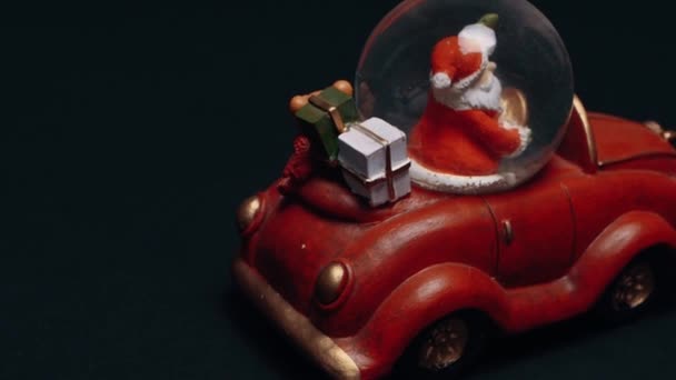 Perfektní hračka, červené retro auto, Santa Claus za volantem chráněný křišťálovou koulí, dárky v kufru. Dětské hračky, zimní koncept. Vánoce a Nový rok — Stock video