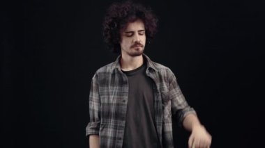 Karizmatik, yakışıklı genç adam elinde iki paket tutuyor diğer eli bir tarafı işaret ediyor ve benzer bir işaret gösteriyor. Alışverişin keyfi. Siyah arka planda izole edilmiş. Konsept: