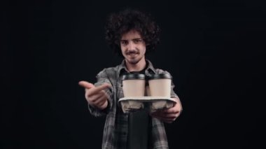 Neşeli çocuk, elinde dört kahveyle oturur ve kahveyi ileri doğru yayar, benzer bir işaret gösterir. Siyah arka planda izole edilmiş. Hayat kavramı. İnsanların duyguları işte. 4k portre