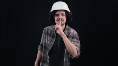Huch, kimseye söyleme. Beyaz kask takan gizli mühendis gizlilik işareti olarak parmağını ağzına koyar. Siyah arka planda izole edilmiş. Hayat kavramı. İnsanların duyguları işte. 4k