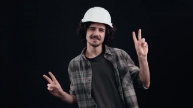 Neşeli, karizmatik mühendis parmaklarını huzur içinde getiriyor ve alçakgönüllü ve mutlu bir şekilde dans ediyor. Siyah arka planda izole edilmiş. Hayat kavramı. İnsanların duyguları işte. 4k portre