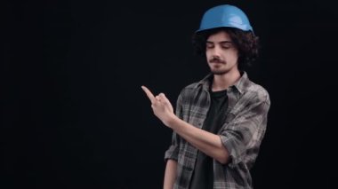 İyimser genç adam sağ tarafı gösteriyor, neşeli tabela neşeli görünüyor. Siyah arka planda izole edilmiş. Hayat kavramı. İnsanların duyguları işte. 4k portre