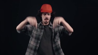 Uzun saçlı kıvırcık genç adam, şapkasını iyimser bir şekilde kafasına koyar, mutlu bir şekilde gülümser ve benzer bir tabelaya hevesle bakar. Siyah arka planda izole edilmiş. Hayat kavramı. Halklar