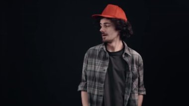 Kırmızı şapkalı, işaret parmağı bir tarafta olan karizmatik genç adam 