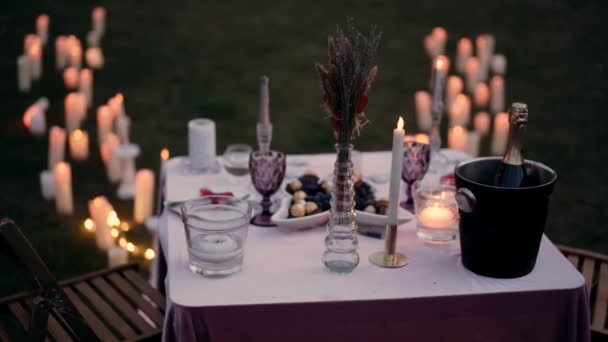 Romantyczne nakrycie do stołu urządzone na oświadczyny. Ozdobione świecami, sztućcami, szklankami, szampanem i słodyczami. Portret 4k — Wideo stockowe