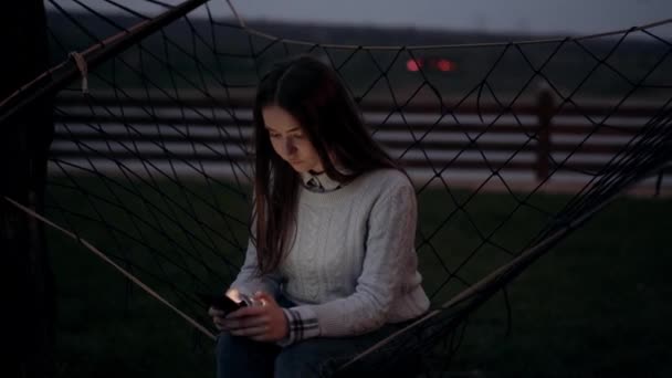 Sérieux belle jeune fille tapant au téléphone, le soir, dans le berceau de la nature. Paysage nocturne dans la nature. Portrait 4k — Video