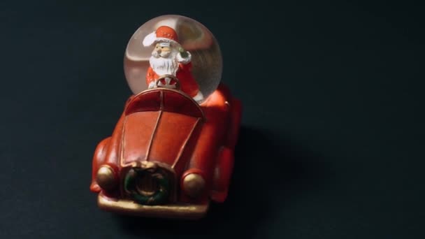 Brinquedo na forma de um carro retro ao volante do qual o Papai Noel se senta, cumprimenta as crianças e tem presentes no porta-malas. Brinquedos infantis, conceito de inverno. Natal e Ano Novo — Vídeo de Stock