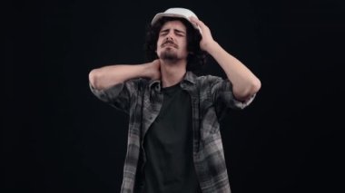 Sırt ağrısı çeken beyaz kasklı genç bir mühendisin portresi. Çocuk acı içinde elini boynuna dayadı. Siyah arka planda izole edilmiş. Hayat kavramı. İnsanların duyguları işte. 4k portre