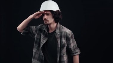 Meraklı mühendis elini alnına koyuyor ve uzaklığı görüyor. Siyah arka planda izole edilmiş. Hayat kavramı. İnsanların duyguları işte. 4k portre