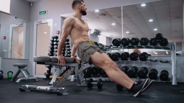 Marco cercano del joven deportista que se sienta con las manos en el soporte deportivo, posición diagonal. Intensa energía masculina. Estilo de vida saludable. Concepto deportivo — Vídeos de Stock