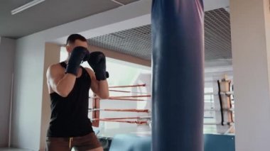 Spor salonunda kum torbasında antrenman yapan hırslı bir genç dövüşçünün portresi. Yoğun erkeksi enerji. Sağlıklı bir yaşam tarzı. Spor konsepti