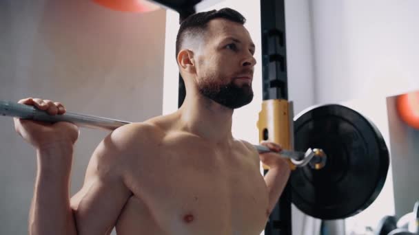 Le profil d'un homme musclé avec la barre de poids dans le dos tourné vers l'avant, prêt à commencer l'exercice. Un entraînement intensif. Intense énergie masculine. Mode de vie sain. Concept sportif — Video