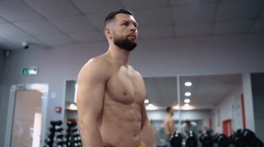 The profile frame of the bodybuilder who looks seriously ahead, has a bare chest, in the gym. Intense masculine energy. Healthy lifestyle. Sport concept