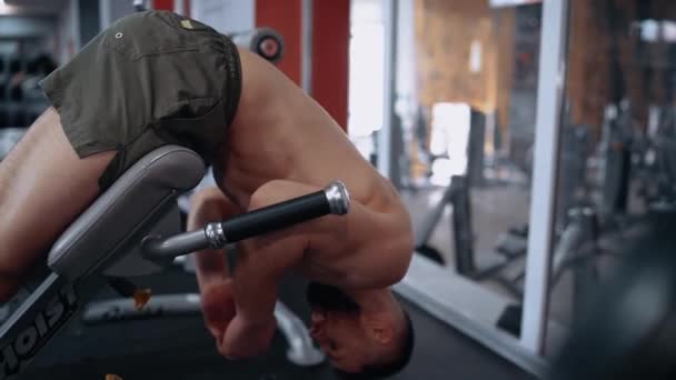 De vastberaden man met de baard voert het achterste deel uit op de bank, in de sportschool. Intense mannelijke energie. Een gezonde levensstijl. Sport concept — Stockvideo