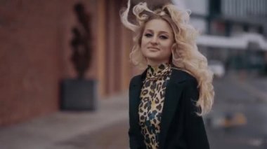 Şık saç stili ve parlak makyajlı genç sarışın, dumanlı gözlü, odaya geri dönüyor, gülümsüyor, sırtını dönüyor. Kadın enerjisi. Güzellik endüstrisi. Sanatsal kavram