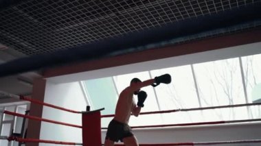 Dans pistinin altından çekilen genç dövüşçü yumruklarıyla ritmik boks hareketleri sergiliyor. Yoğun erkeksi enerji. Sağlıklı bir yaşam tarzı. Spor konsepti