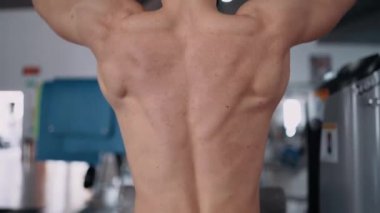 Yakışıklı vücut geliştiricinin sırt kaslarını spor salonuna pompalarkenki yakın çekimi. Yoğun erkeksi enerji. Sağlıklı bir yaşam tarzı. Spor konsepti