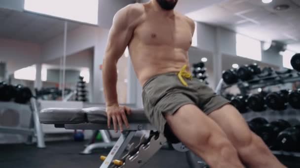 Le beau jeune homme entraîne son corps à effectuer des redressements assis avec les mains sur une chaise. Intense énergie masculine. Mode de vie sain. Concept sportif — Video