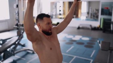 Kaslı genç adam sırtını çalıştırır, egzersizi bitirir ve spor malzemelerinden kalkar. Yoğun erkeksi enerji. Sağlıklı bir yaşam tarzı. Spor konsepti