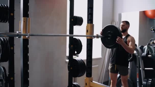 L'atleta prepara il suo posto di allenamento, mette pesi sulla barra di sollevamento. Formazione intensiva. Intensa energia maschile. Uno stile di vita sano. Concetto sportivo — Video Stock