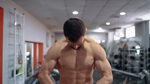 De jonge man met de blote borst spannen zijn rug en nek en dan steekt zijn handen op en belast zijn biceps, voorste frame. Intense mannelijke energie. Een gezonde levensstijl. Sport concept — Stockvideo