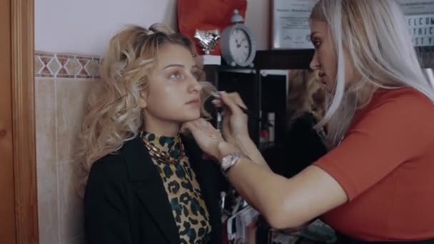 The blonde make-up artist applies the womans makeup base with a brush. The process of applying makeup at home. Artistic concept — Stock Video