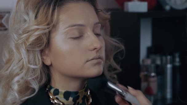 La jeune esthéticienne applique la poudre sur toute la face du modèle, après quoi elle tonifie le correcteur sous les yeux. Processus d'application du maquillage à la maison par un professionnel. Artistique — Video