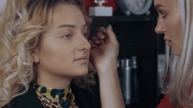 Makyöz, modellerin kaşlarını ince bir fırçayla düzeltir ve sonra onları kahverengi bir kalemle boyar. Bir profesyonelin evde makyaj yapma süreci. Sanatsal kavram