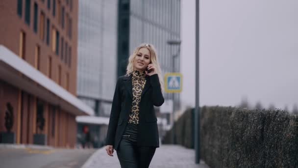 Die charismatische junge Frau, Geschäftsfrau, bespricht das nächste Projekt, telefonisch, auf der Straße, vor dem Hintergrund der lauten Stadt, in einer Jacke gekleidet und schrill geschminkt — Stockvideo