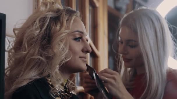 De jonge make-up kunstenaar brengt valse wimpers aan op de charismatische blondine. Het proces van het aanbrengen van make-up thuis door een professionele .Beauty industrie. Artistiek concept — Stockvideo